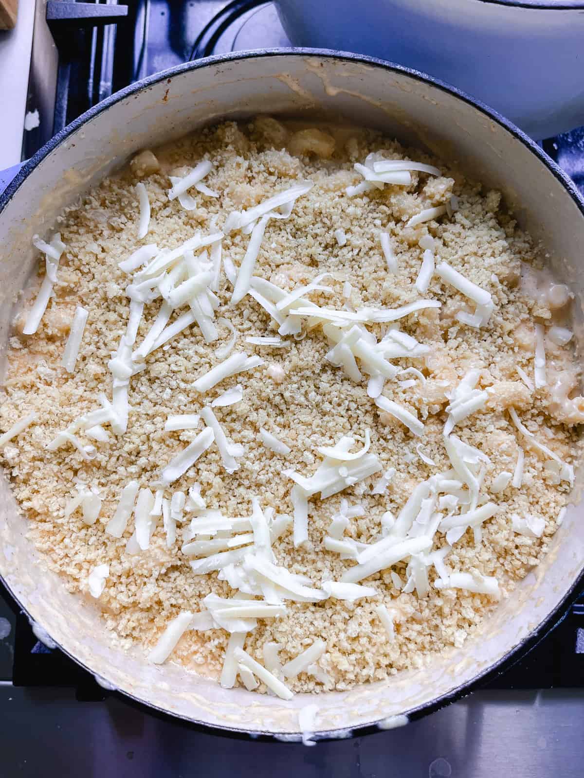 Dutch oven mac and cheese with extra cheese and bread crumbs sprinkled on top.