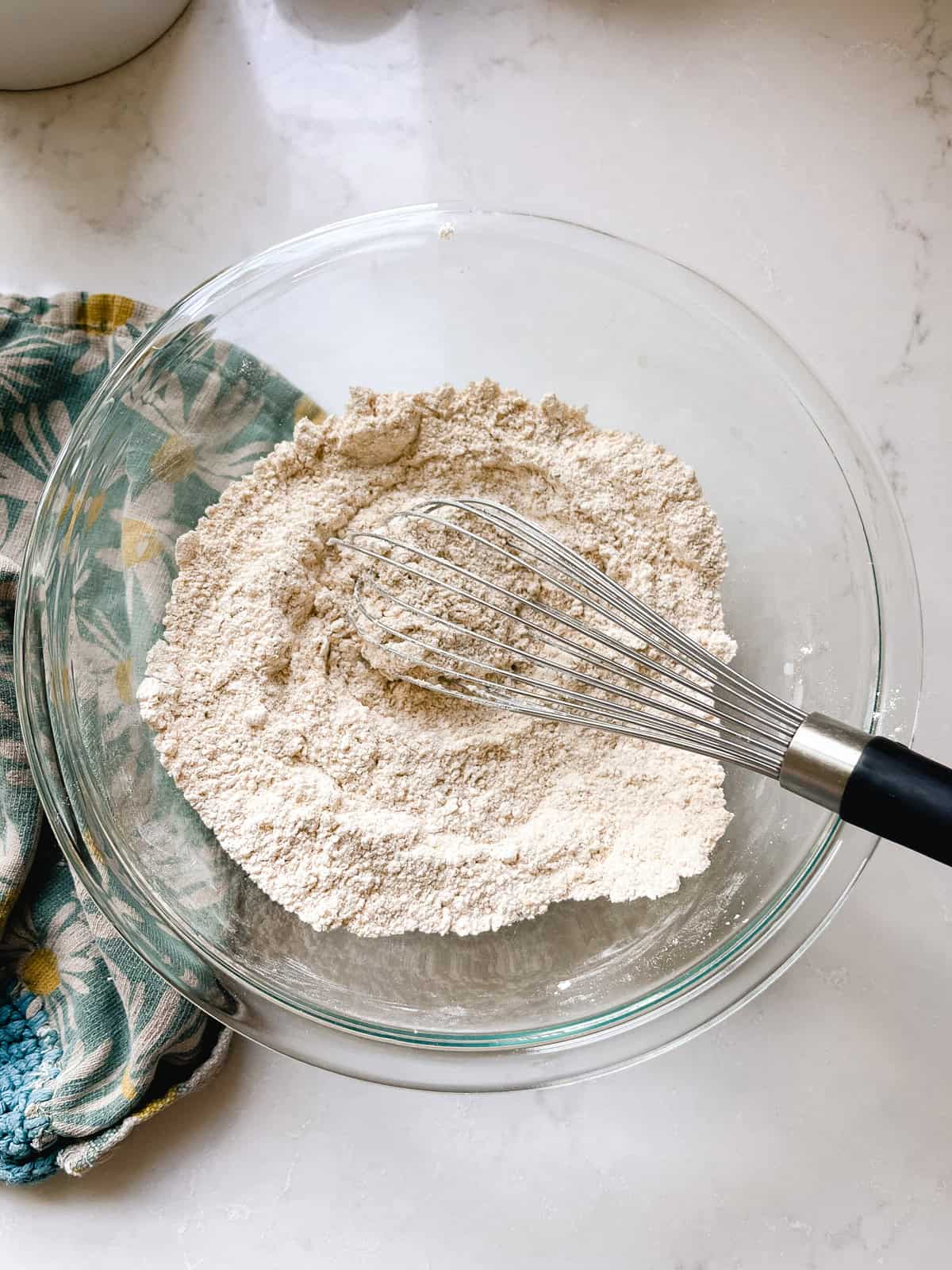 Stirring dry ingredients in a mixing bowl with a whisk.