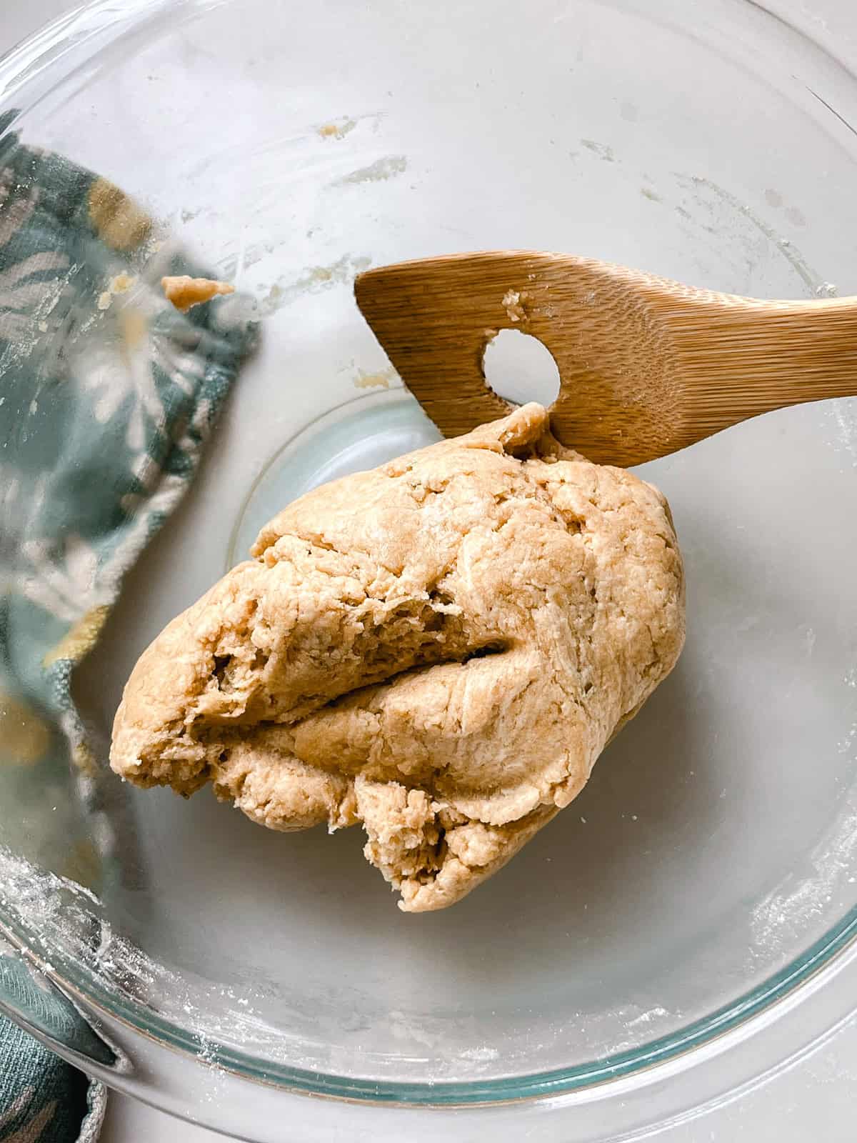 Fresh milled flour cracker dough in a bowl with a wooden spoon.