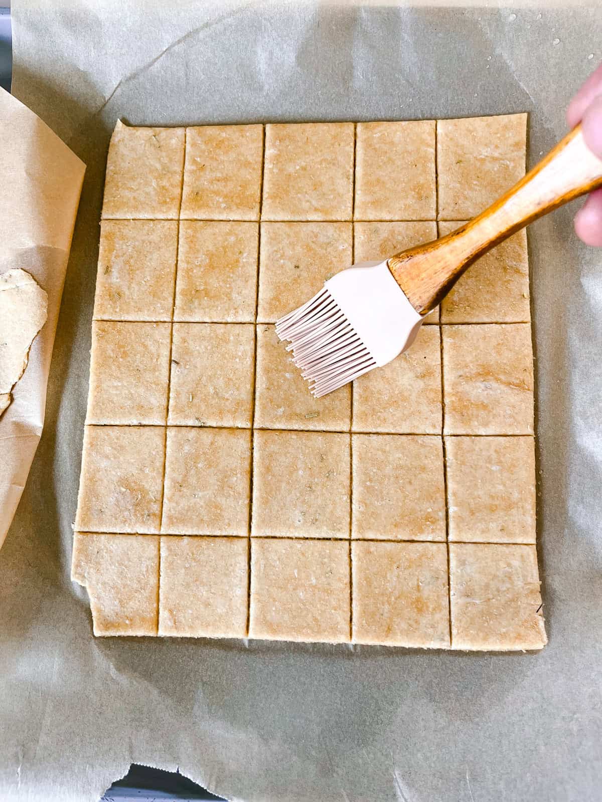 Brushing fresh milled flour crackers with wate using a silicone pastry brush.