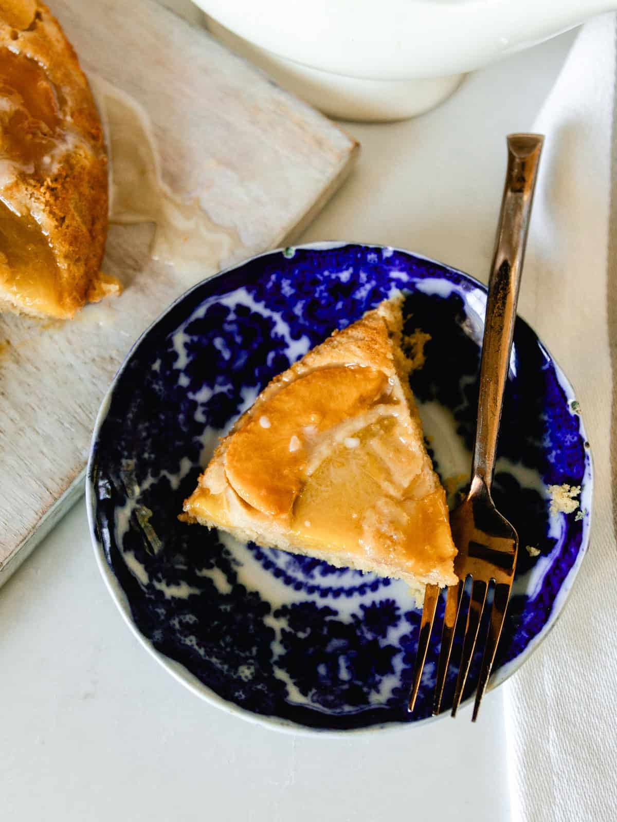 A slice of peach upside down cake on a blue plate with a fork.