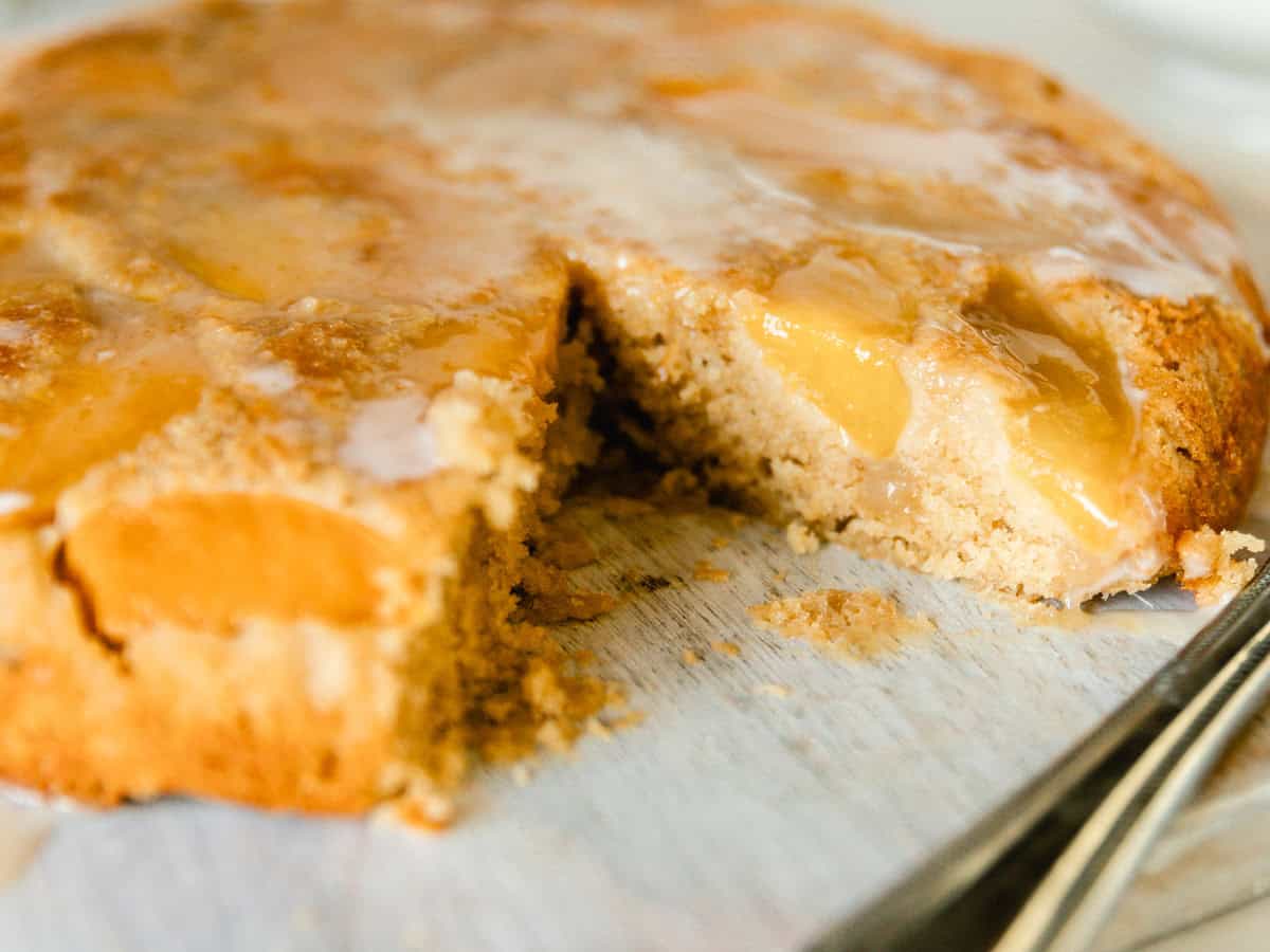 A peach upside down cake with a slice taken out of it.