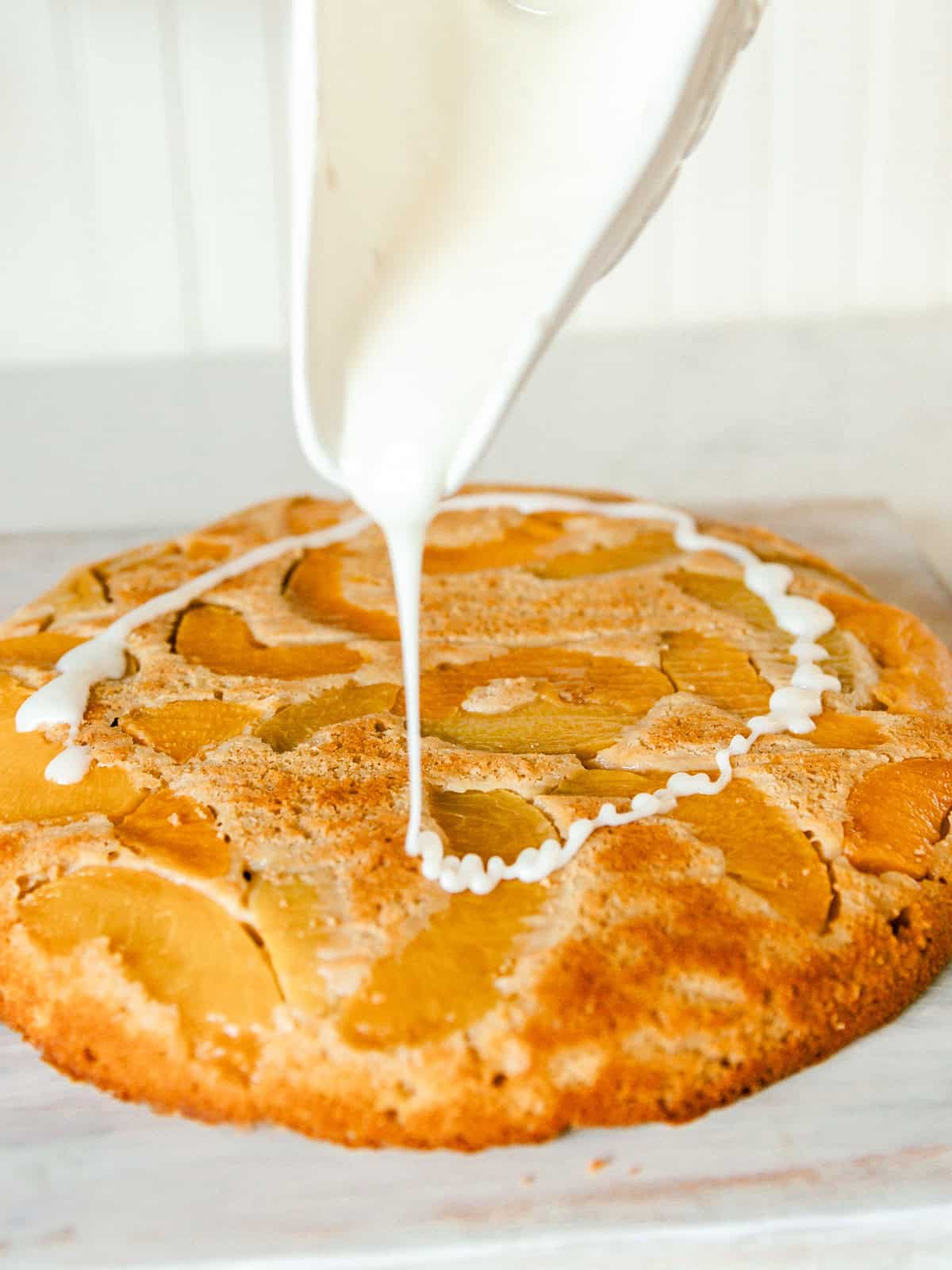 Pouring glaze onto a baked peach upside down cake.