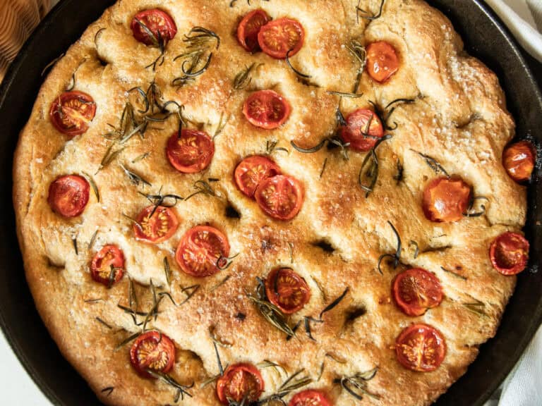 A close up of freshly milled focaccia bread in a cast iron skillet.
