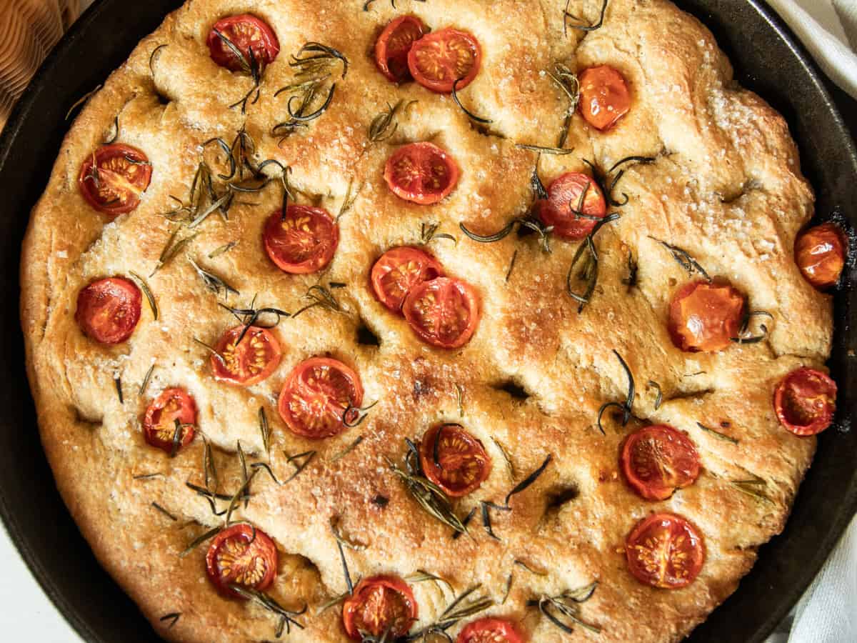A close up of freshly milled focaccia bread in a cast iron skillet. 