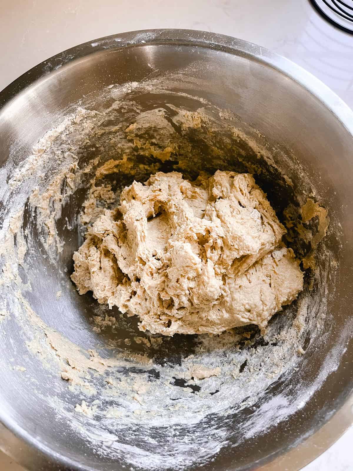 Freshly ground focaccia dough mixed in a metal mixing bowl.
