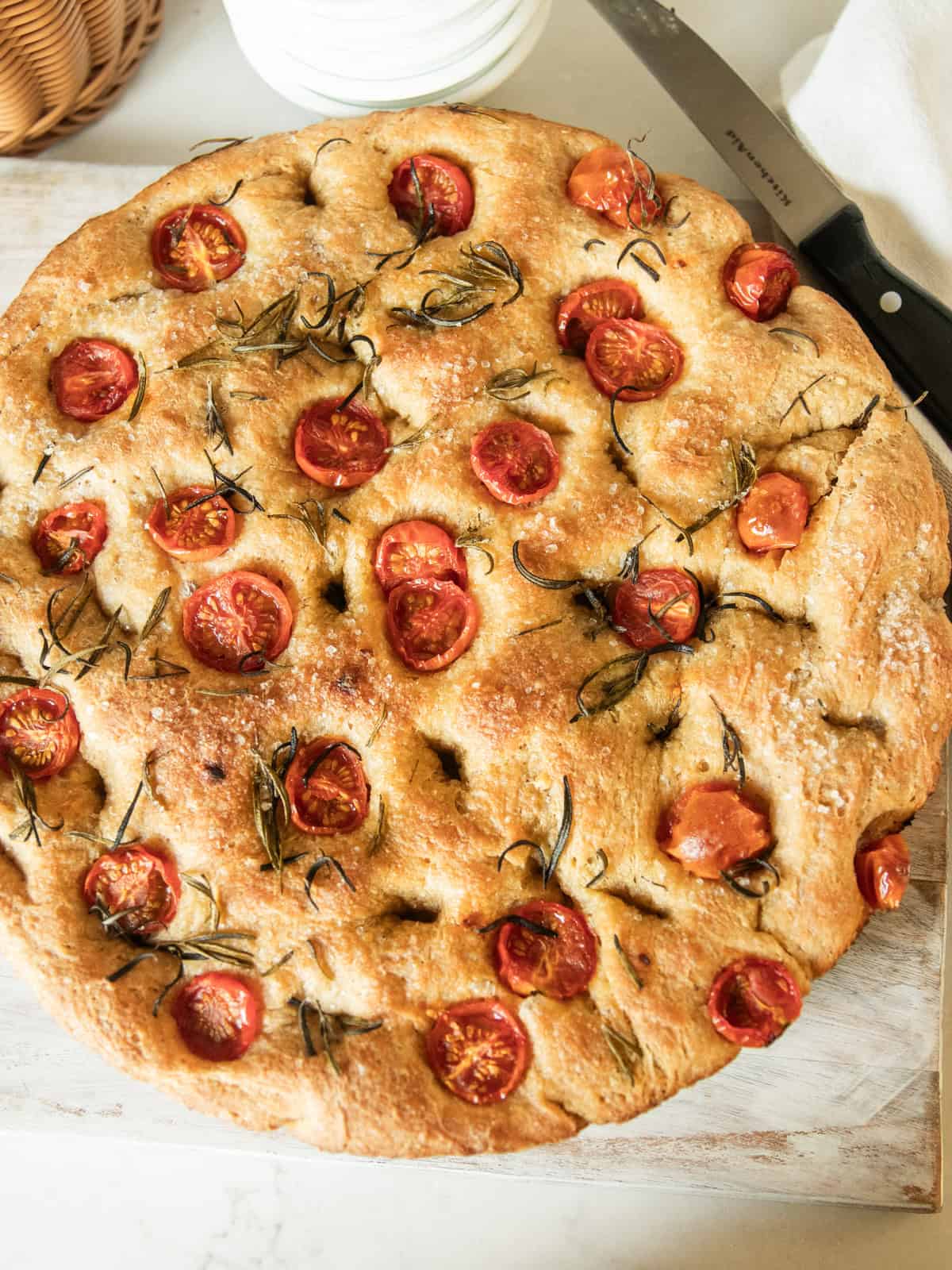 Freshly ground flour focaccia bread on a cutting board with a bread knife.