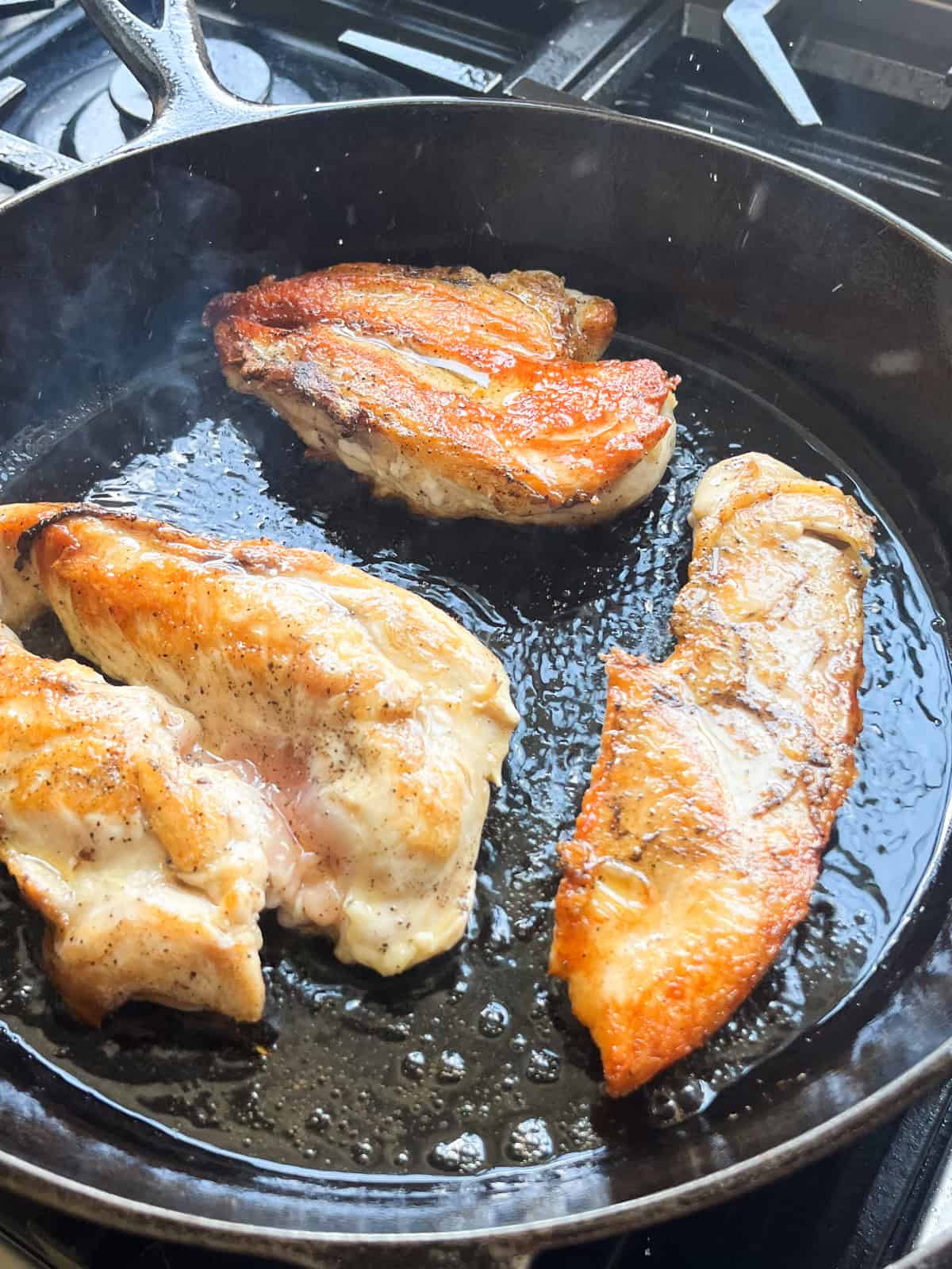 Searing chicken in a cast iron skillet.