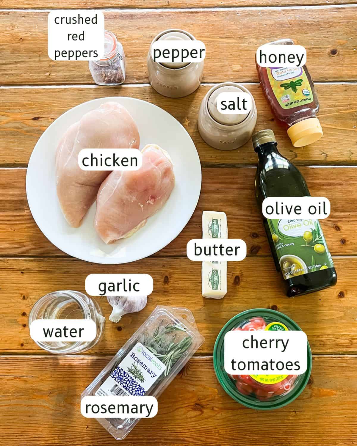 Cherry tomato herb skillet chicken ingredients labeled on a wooden table.