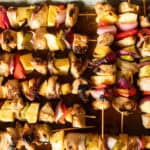 Hawaiian chicken kabobs lined up on a serving tray.
