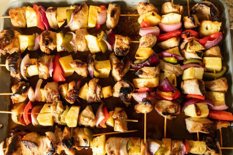 Hawaiian chicken kabobs lined up on a serving tray.
