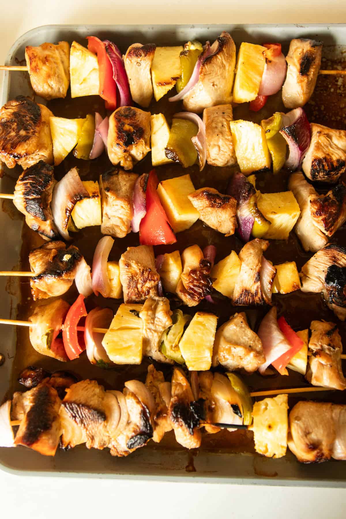 Pineapple chicken kabobs lined up on a baking sheet.