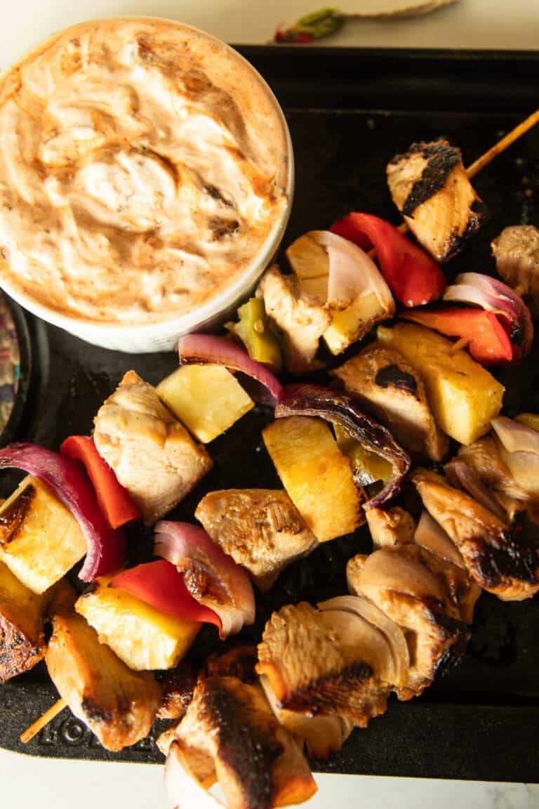 Hawaiian chicken kabobs on a serving tray with a bowl of chipotle cream sauce.