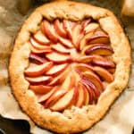 Summer peach galette in a cast iron skillet with a piece of parchment paper under it.