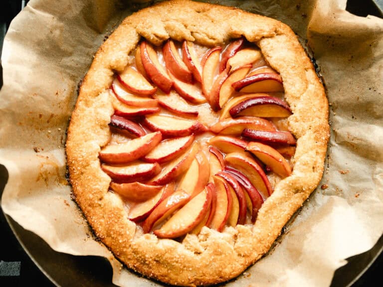 Summer peach galette in a cast iron skillet with a piece of parchment paper under it.