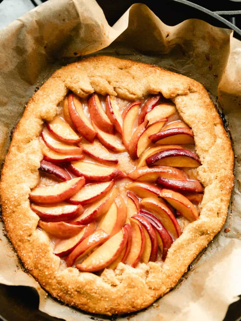 Summer peach galette with whole wheat flour in a parchment-lined cast iron skillet.