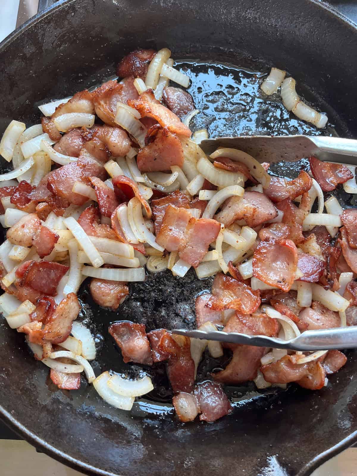 Cooking onions in a cast iron skillet with bacon.