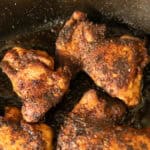 Blackened chicken thighs in a cast iron skillet.