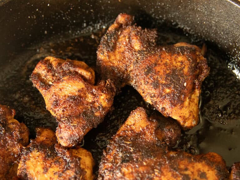 Blackened chicken thighs in a cast iron skillet.