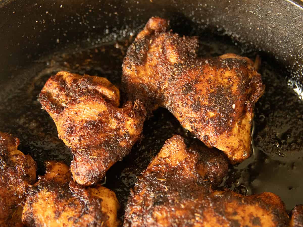 Blackened chicken thighs in a cast iron skillet. 