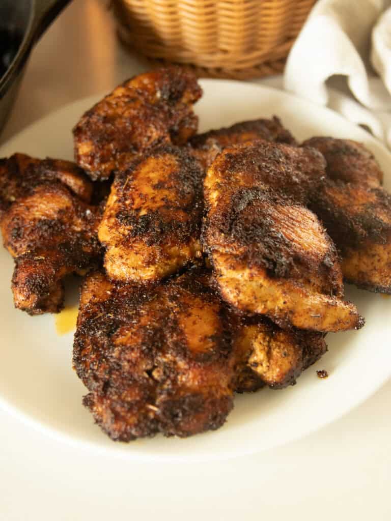 Blackened chicken thighs on a white plate.