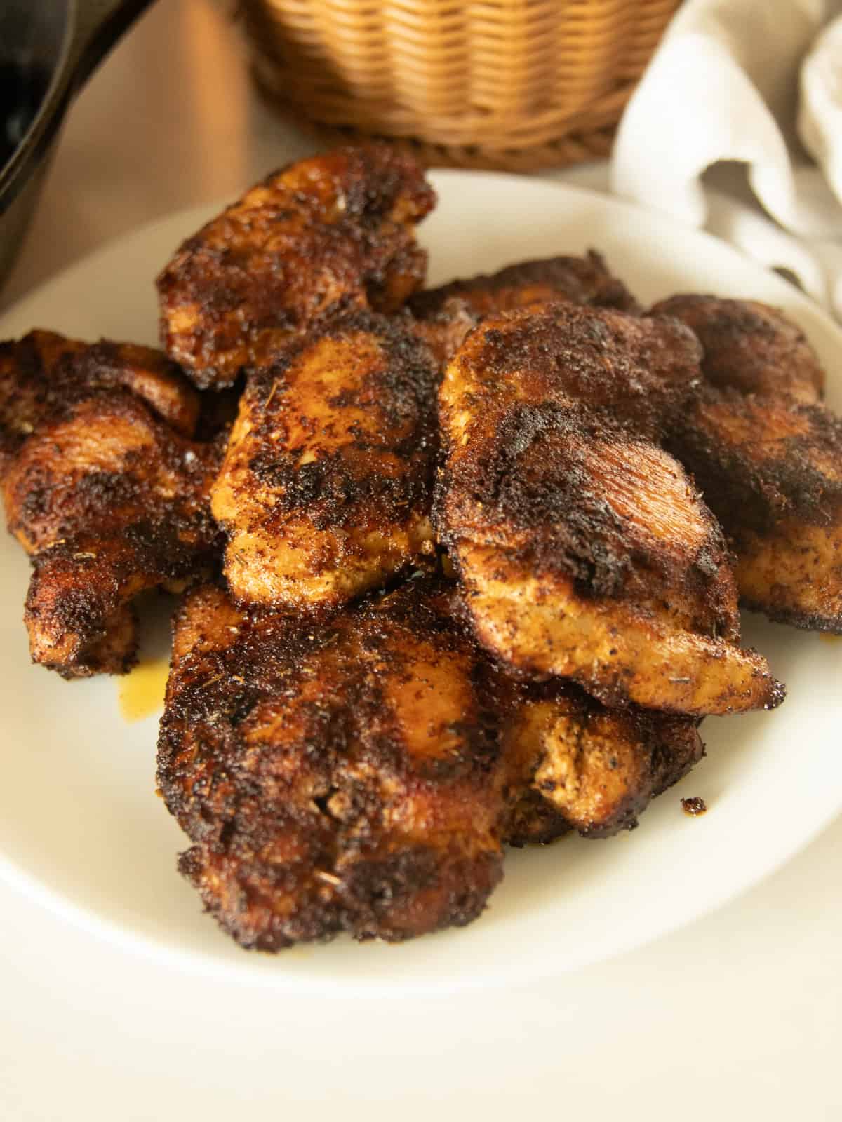 Blackened chicken thighs on a white plate.