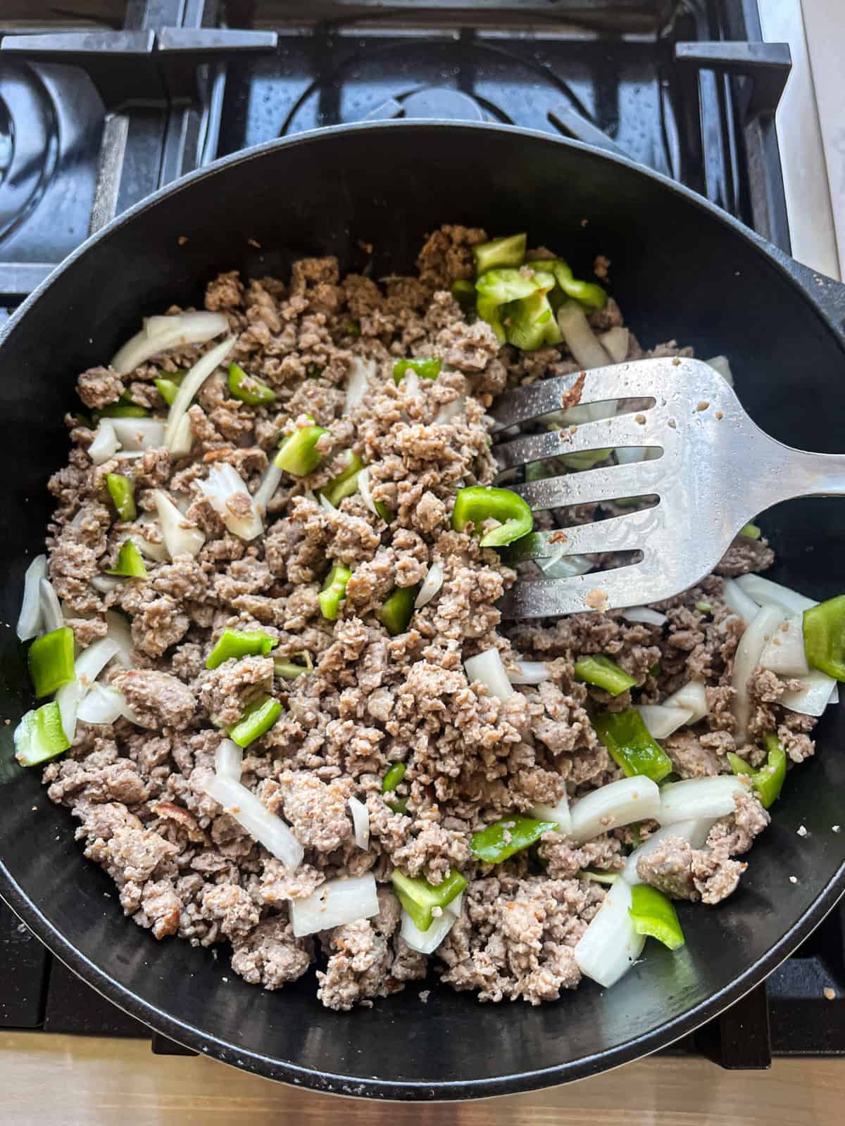 Sauteing peppers and onions with browned sausage.