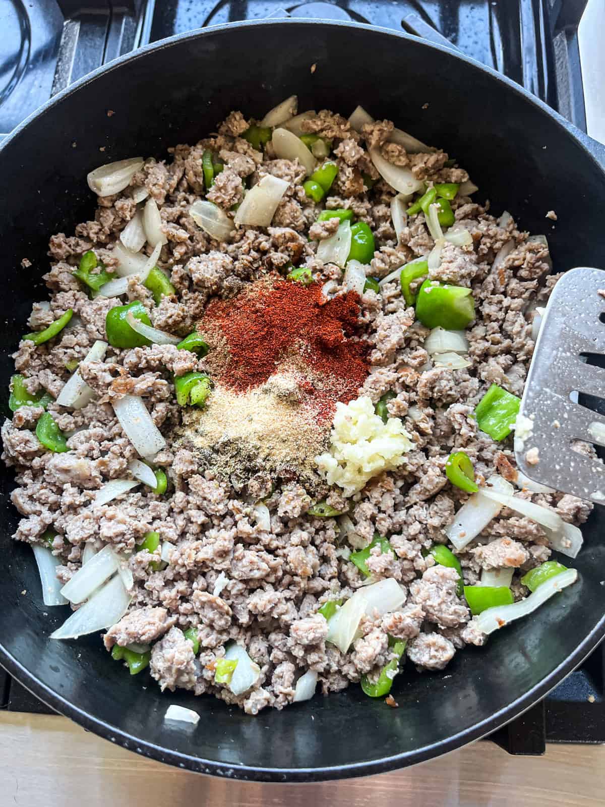 Adding seasoning to sausage and veggie mix.