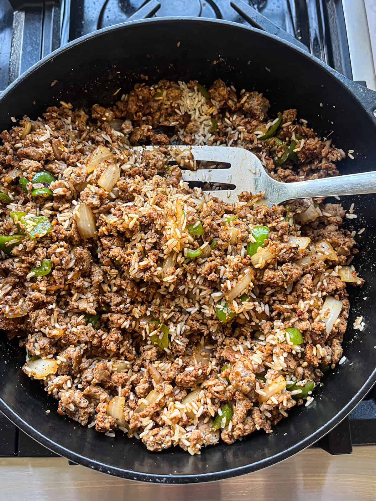Adding uncooked rice to the sausage and veggie mix.