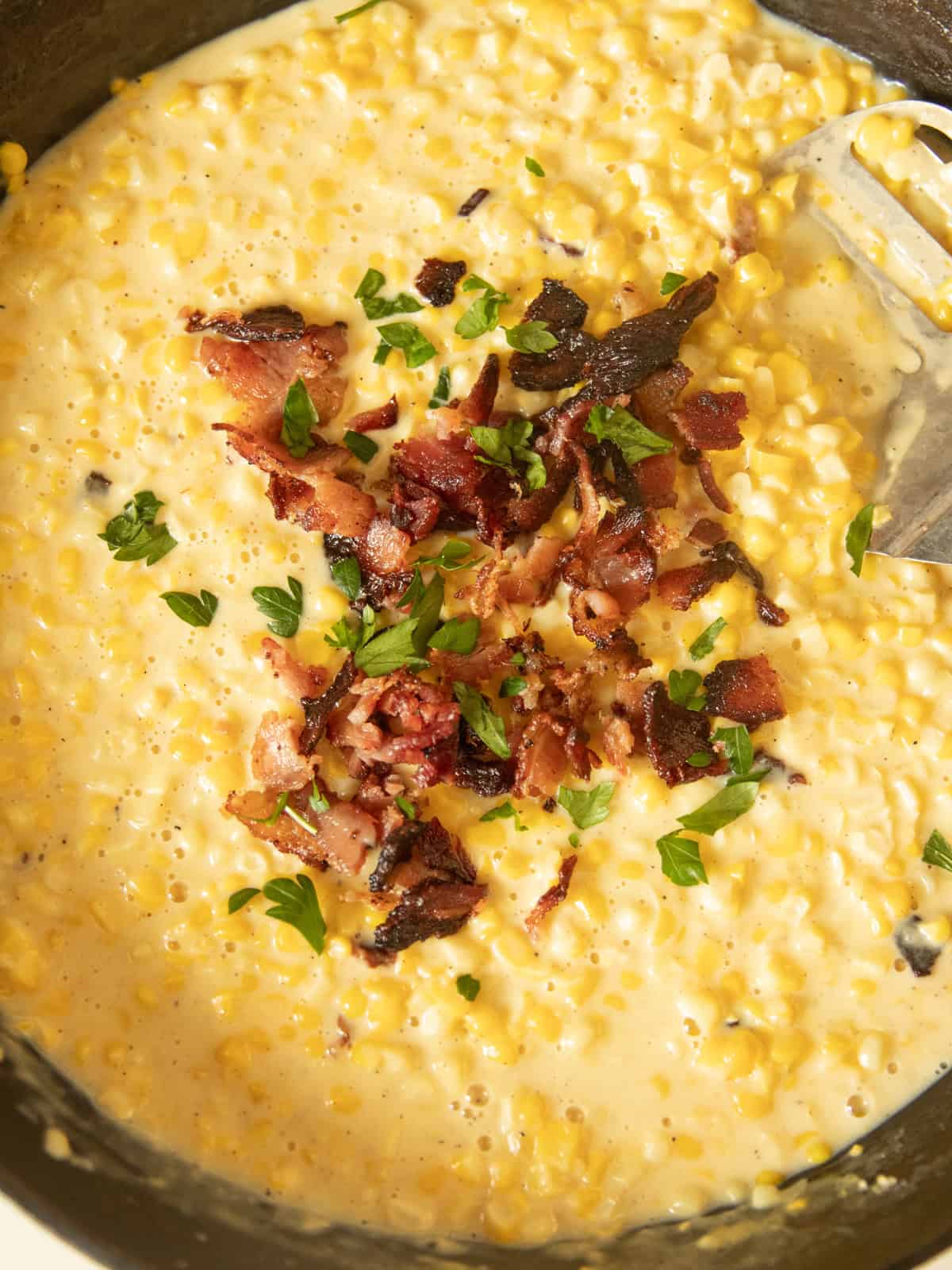 Creamed corn with bacon on top in a cast iron skillet.
