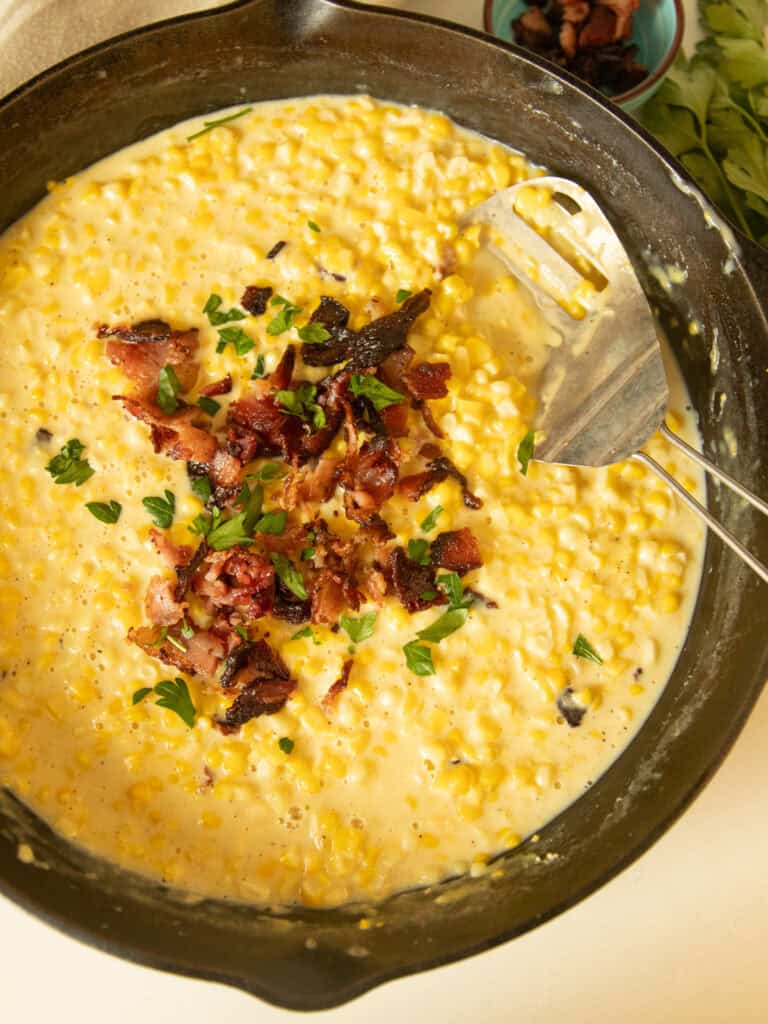 A cast iron skillet with creamed corn in it.