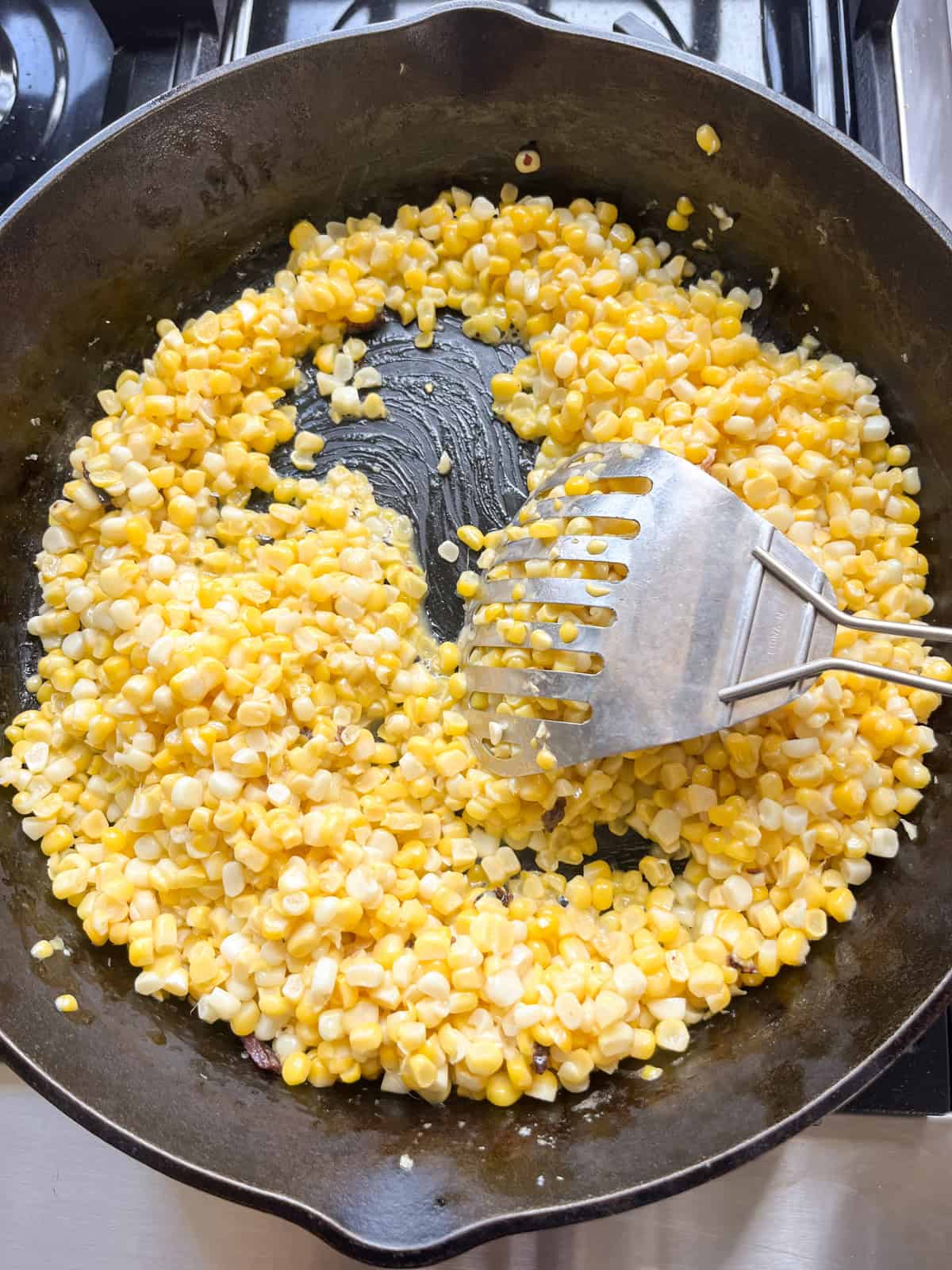Stirring corn kernels in a cast iron skillet.