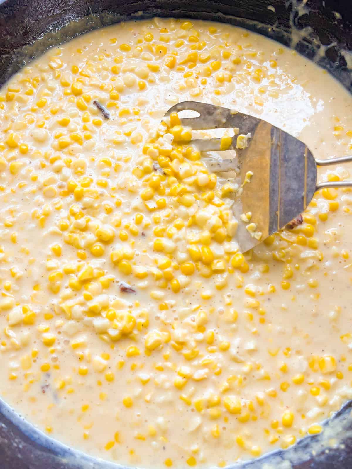 Stirring creamed corn in a cast iron skillet.