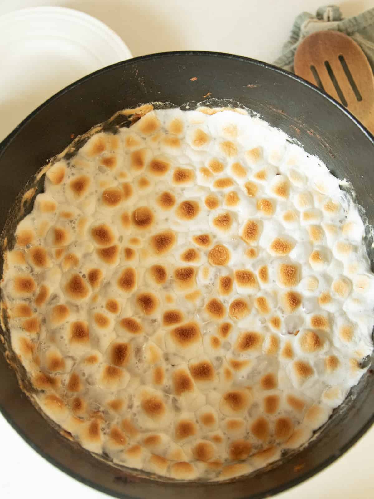 Sweet potato casserole in a dutch oven with browned marshmallows on top.