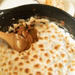 Scooping sweet potato casserole out of a dutch oven.