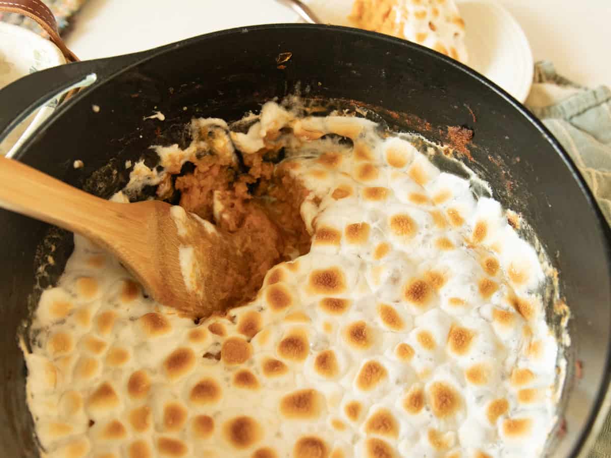 Scooping sweet potato casserole out of a dutch oven.