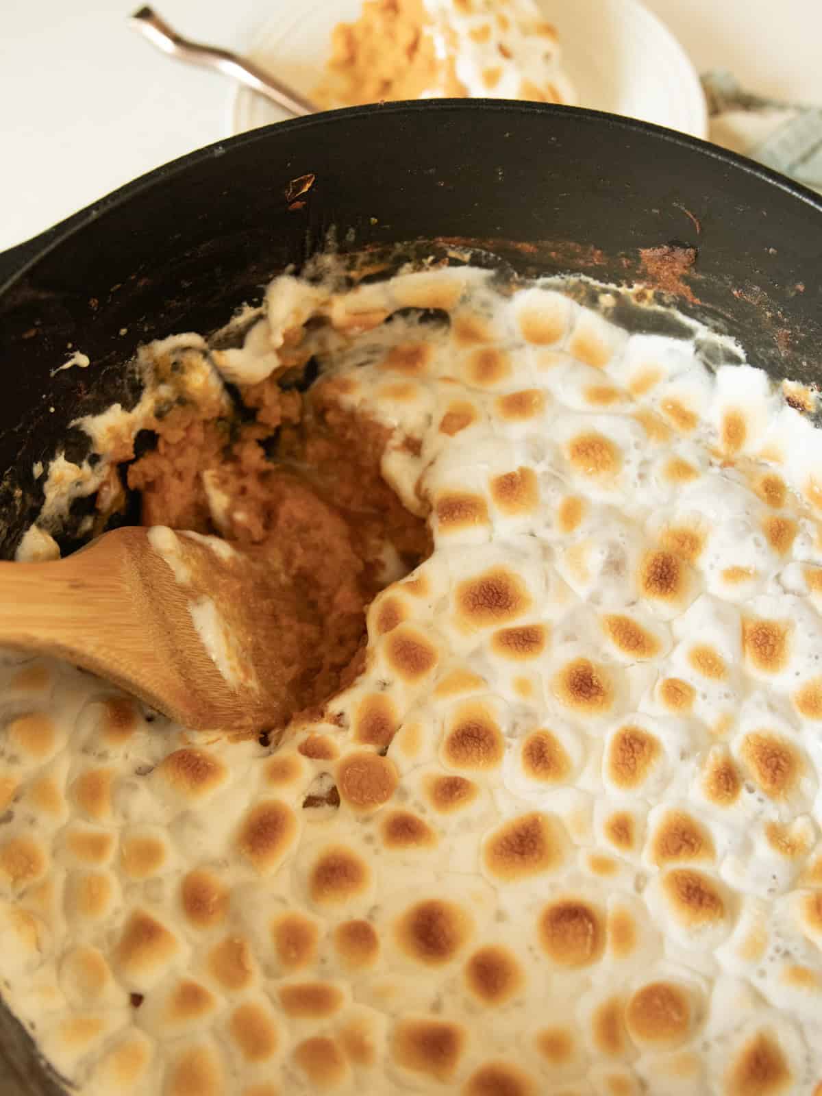 Scooping sweet potato casserole out of a dutch oven.