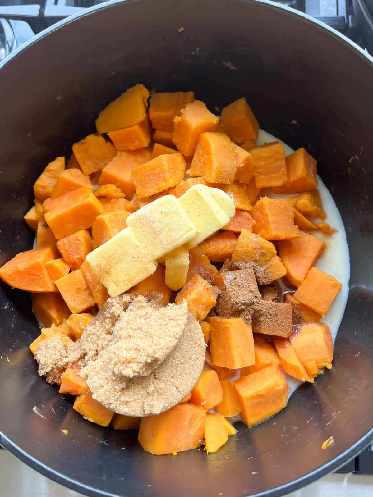 Butter, sugar and milk added to a dutch oven with sweet potatoes.