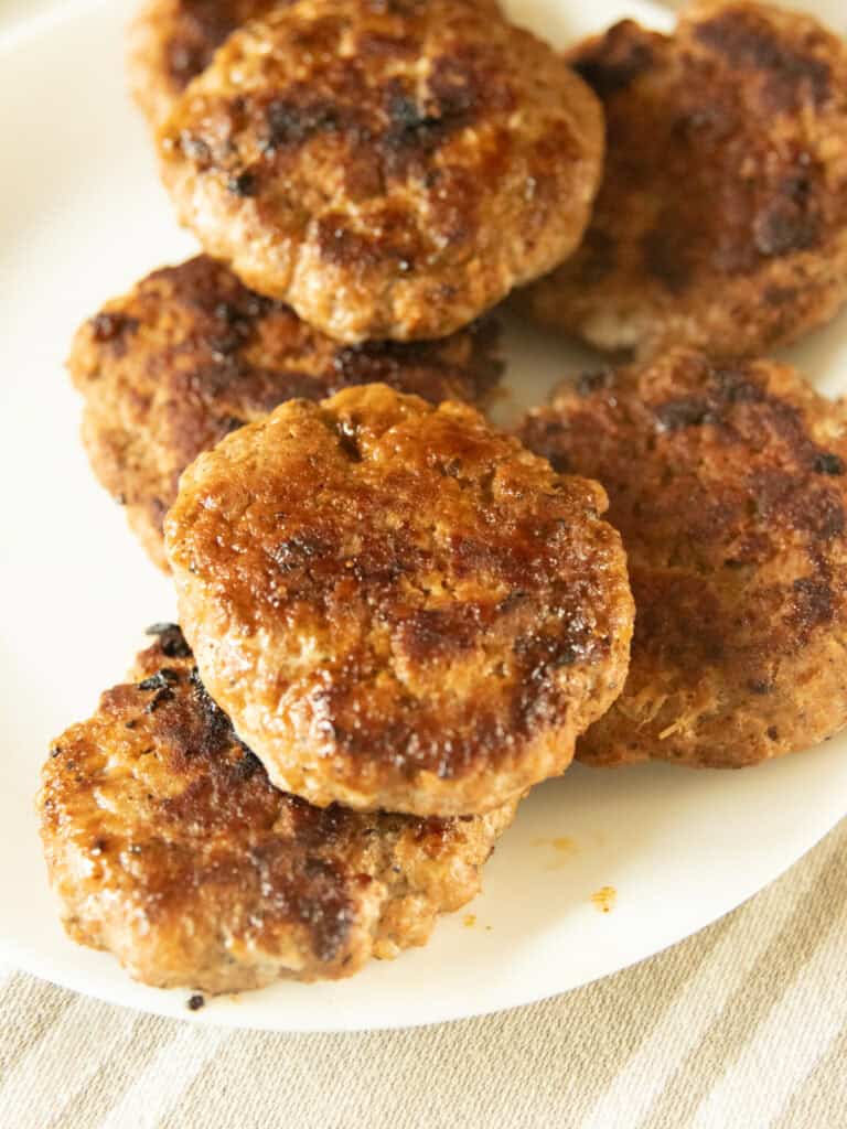 Homemade breakfast sausage patties on a white plate.