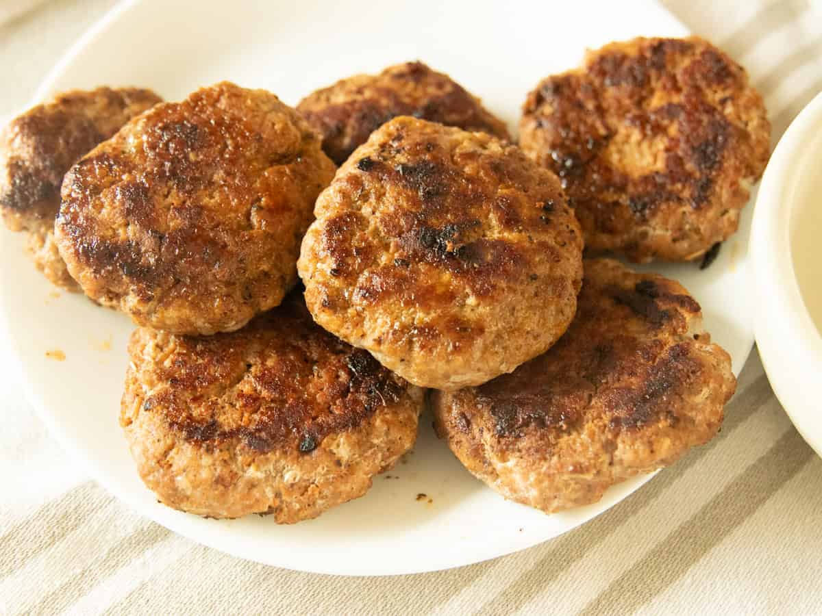 Homemade breakfast sausage patties on a white plate.