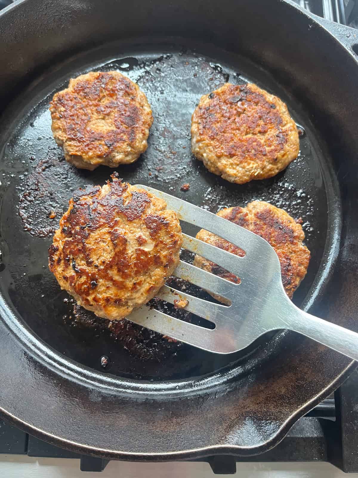 Cooking sausage patties in a cast iron skillet.
