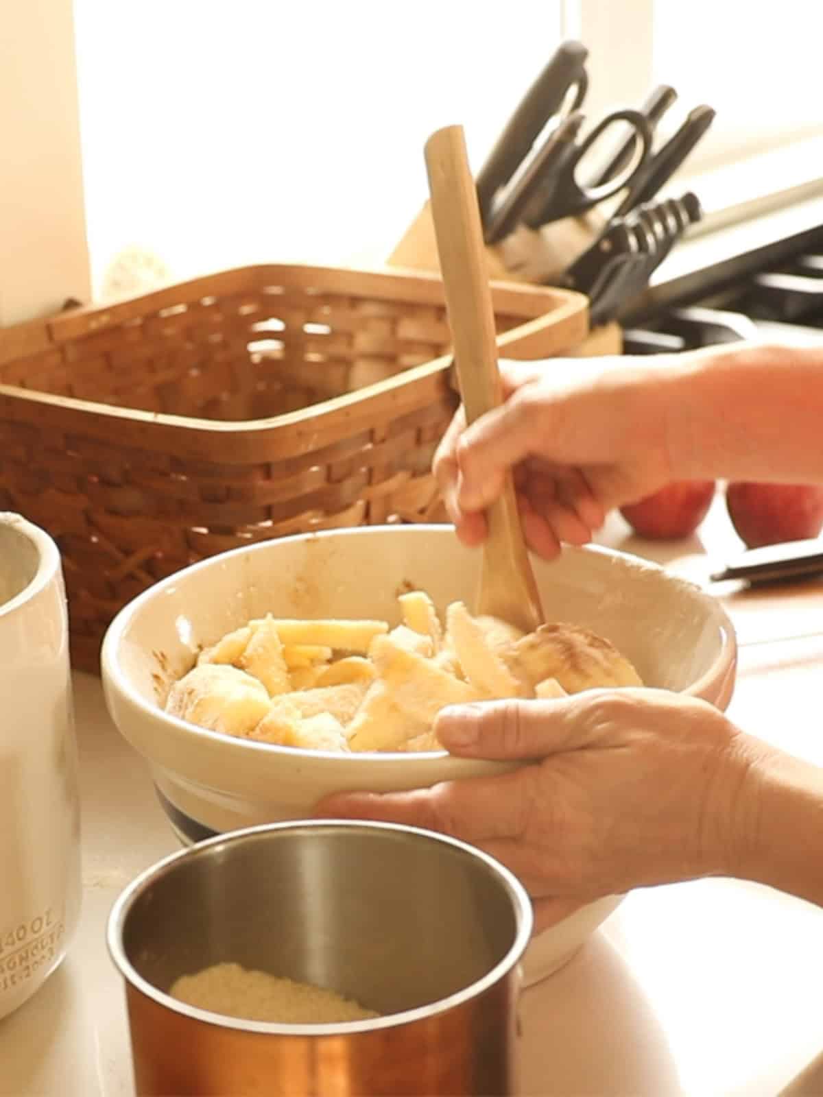 Mixing apples with dry ingredients in a mixing bowl.