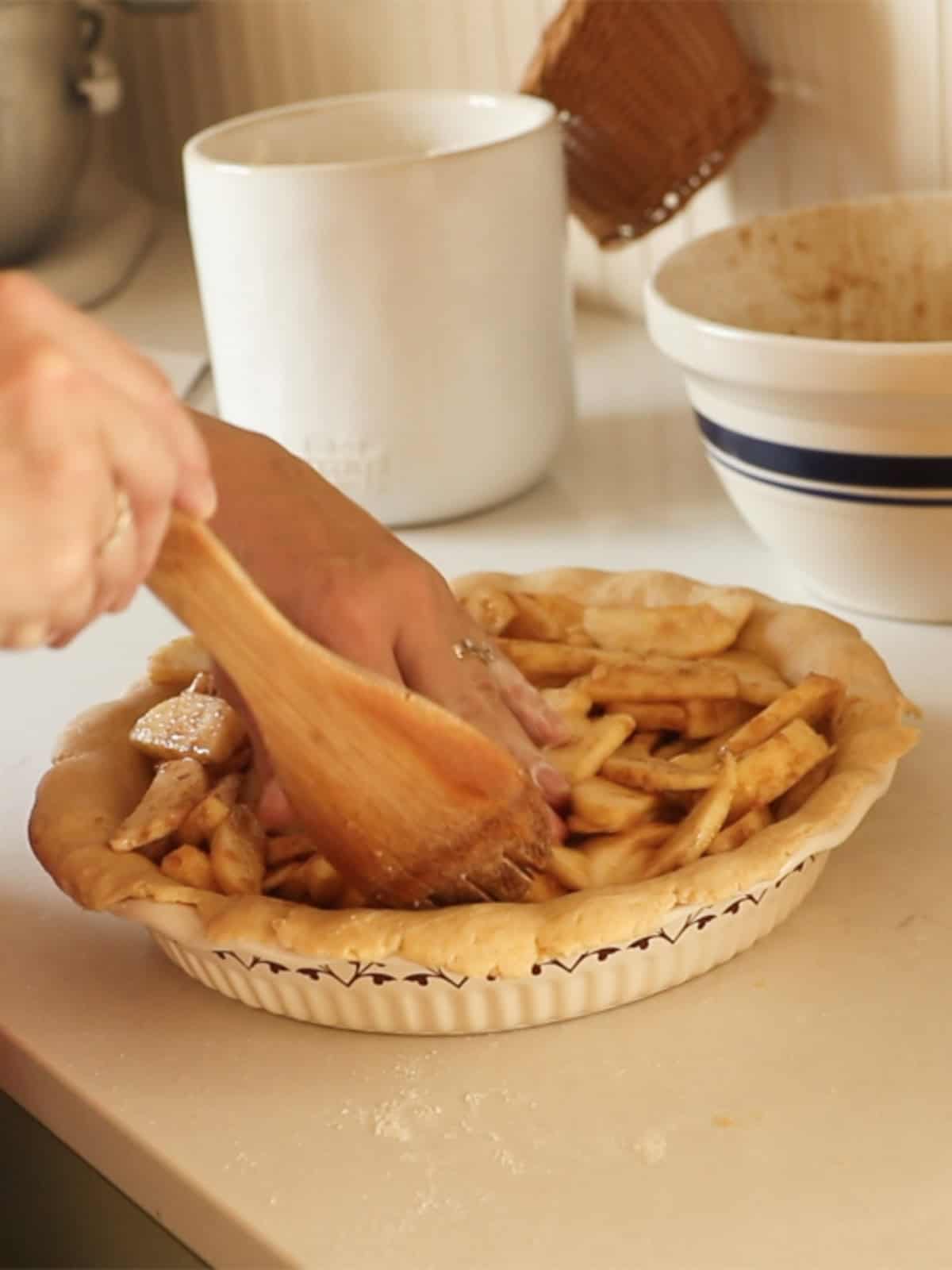 Filling a pie crust with apple pie filling.