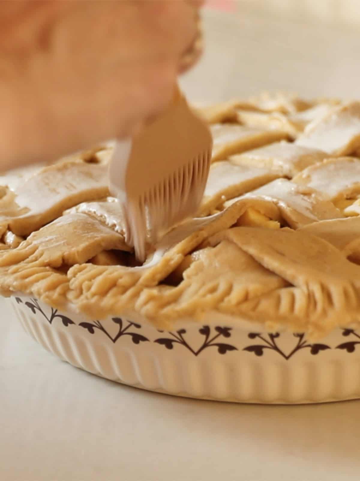 Brushing the top of an unbaked apple pie with an egg wash.