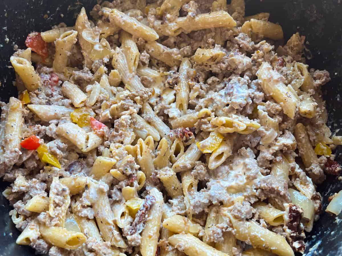 Creamy sausage pasta in a cast iron skillet before adding the cream.
