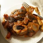 Braised beef shank on a white plate with a fork.