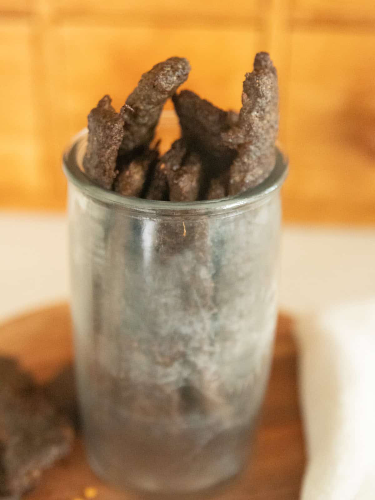 A jar of ground venison jerky on a wooden board.