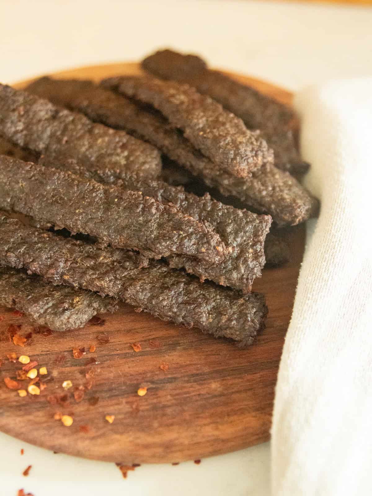Strips of ground venison jerky on a wooden cutting board.