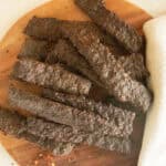 Ground venison jerky pieces on a wooden board.