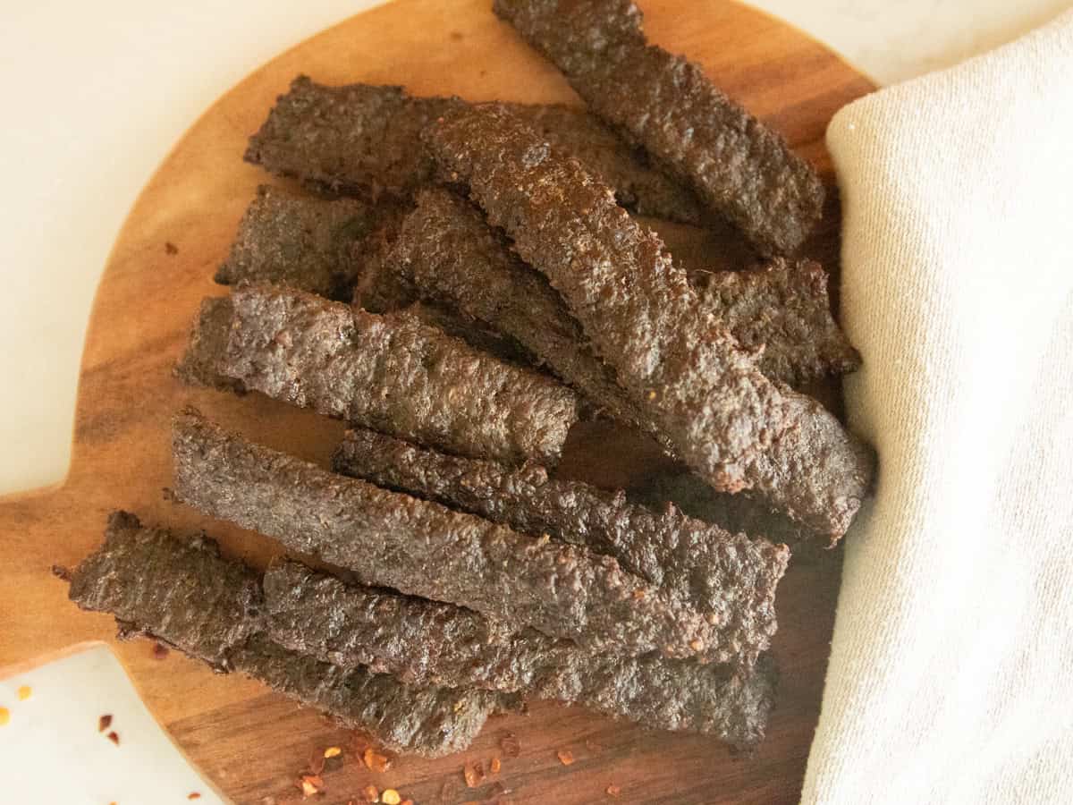 Ground venison jerky pieces on a wooden board.